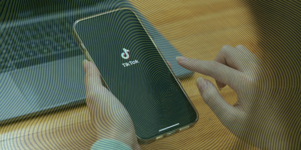 Person scrolling on their phones with TikTok featured on the screen 