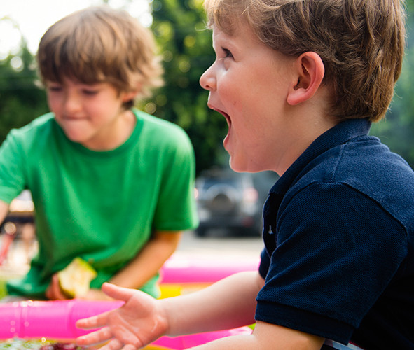 Toddlers playing with toys on a green lawn 